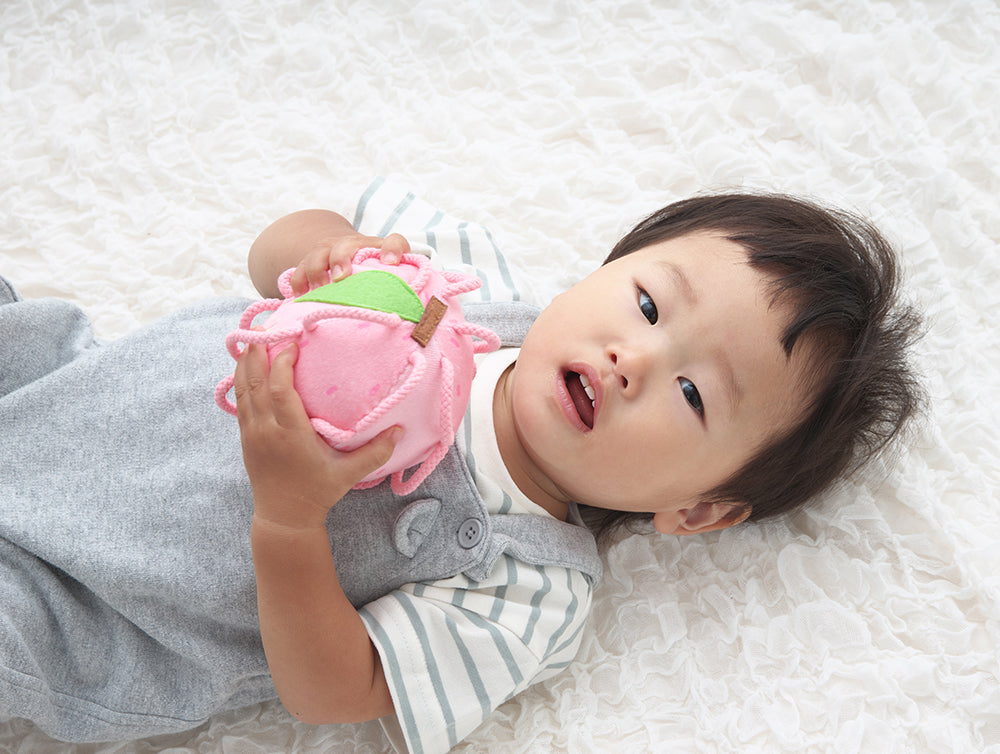 両手にわっかボールももを抱える赤ちゃん