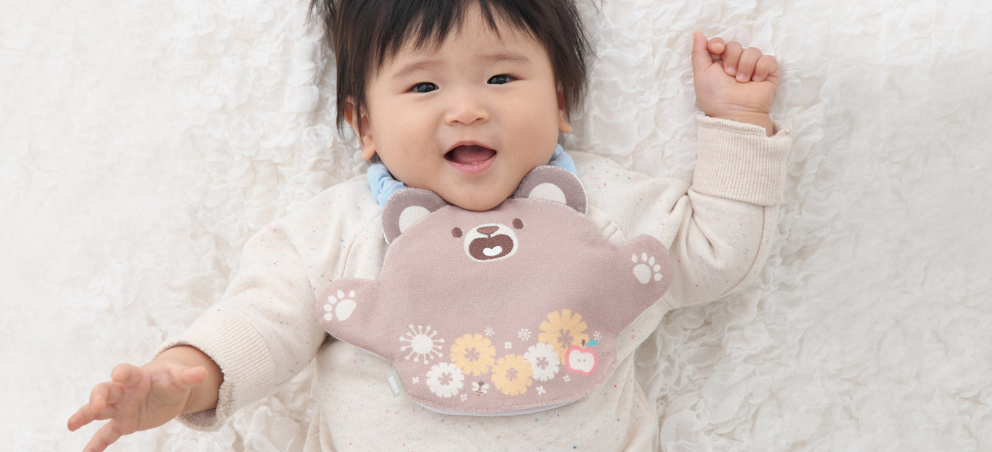 胸元にいないいないばぁスタイくまをかけた赤ちゃん